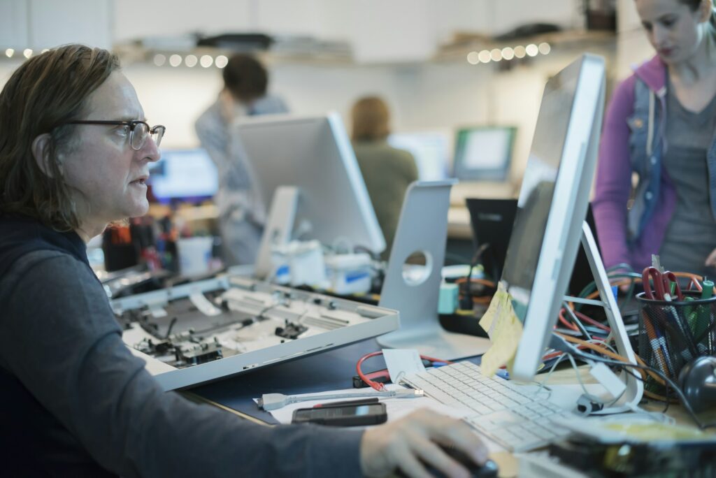 A man seated at a computer, looking at the screen. Computer repair shop.